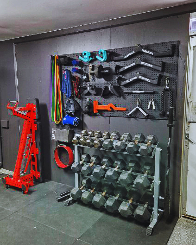 FITEK adjustable bench stored vertically next to dumbbell rack and wall storage