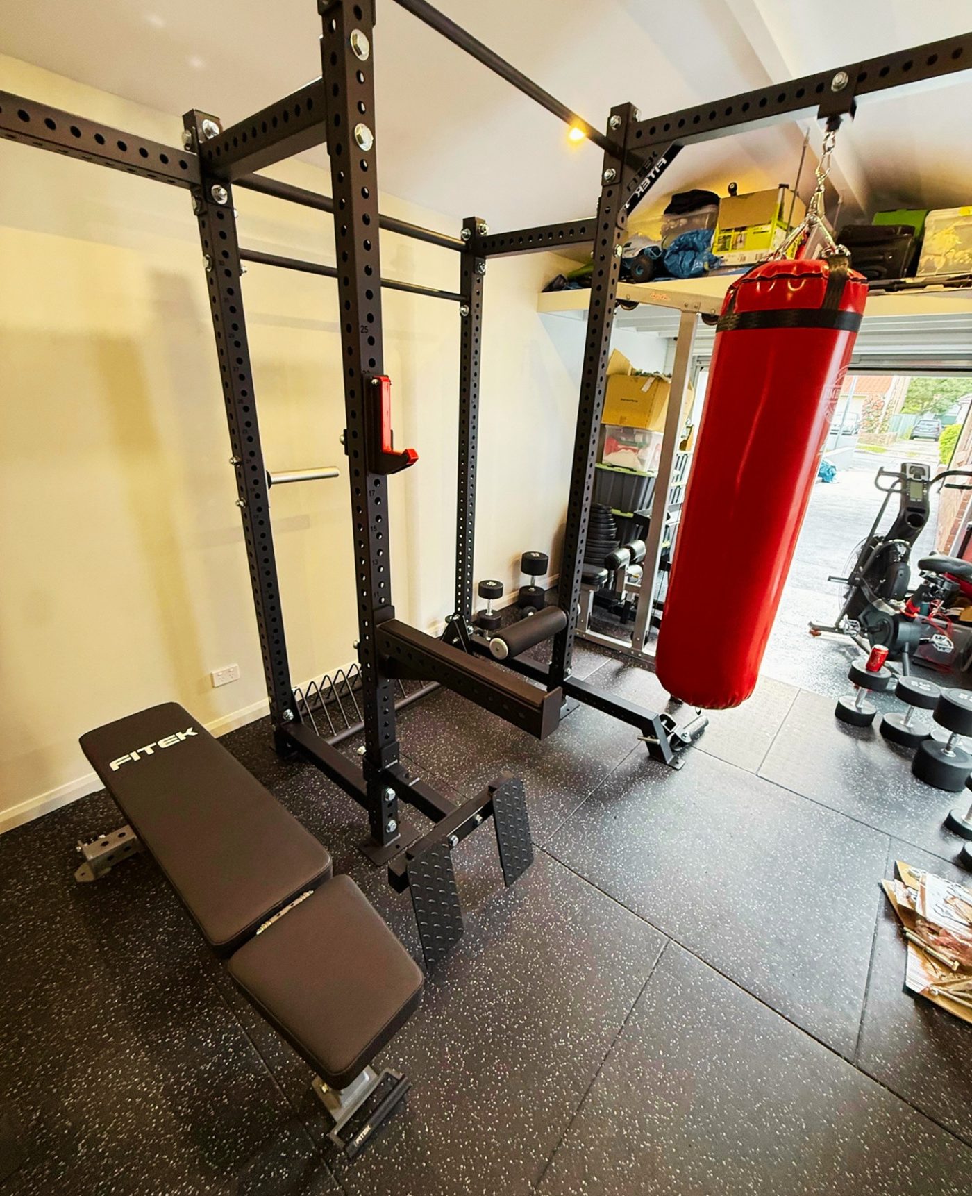 Fully installed FITEK custom garage gym fitout with heavy bag and adjustable bench